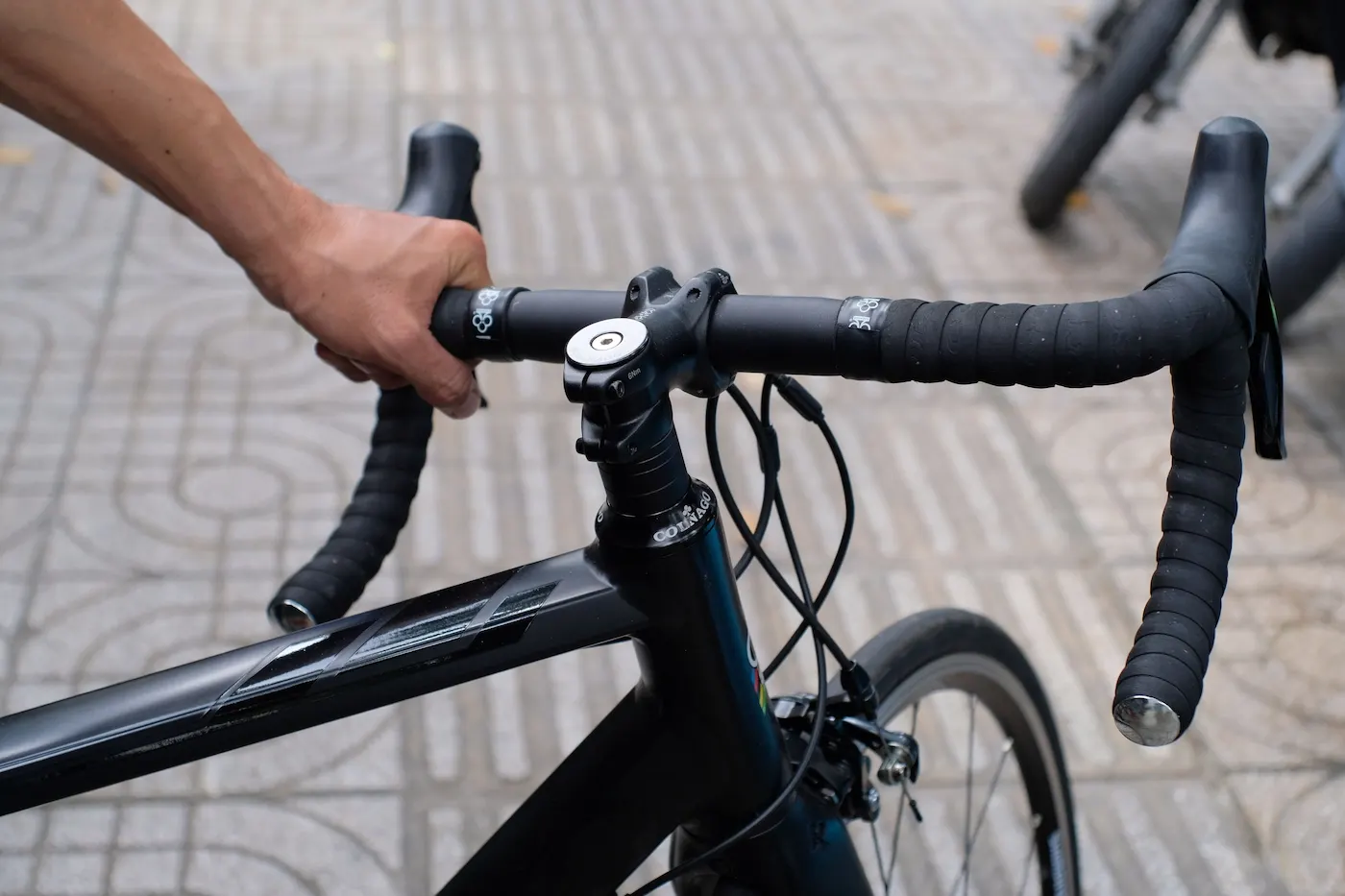 Close-up of a hand resting on the handlebar tops of a road bike.